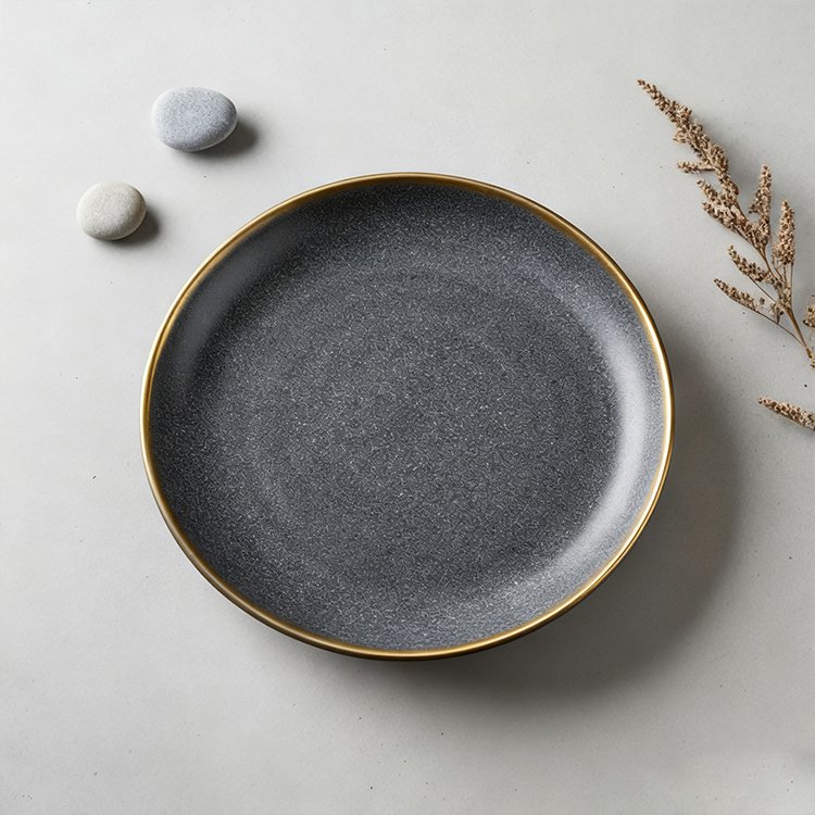 Elegantní černý talíř se zlatým okrajem na stole