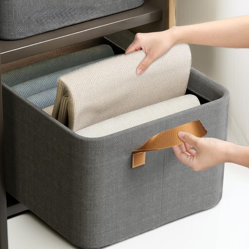 핸드헬드 옷을 가지고 헝겊 수납 바구니를 정리하다