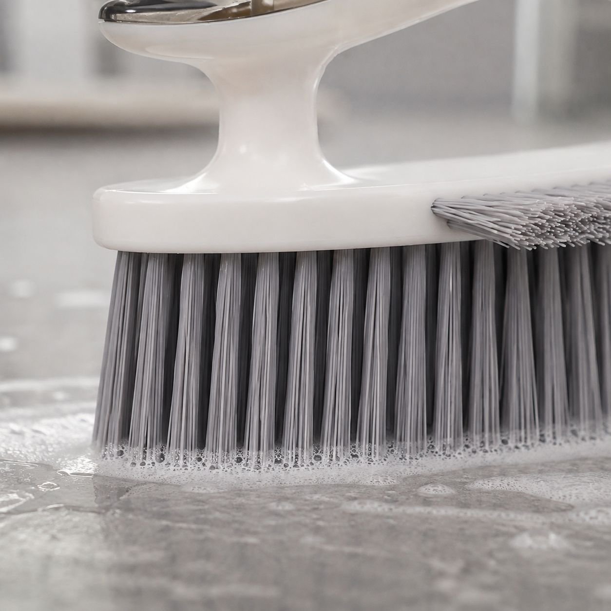 Grout cleaning brush removing dirt from bathroom tiles